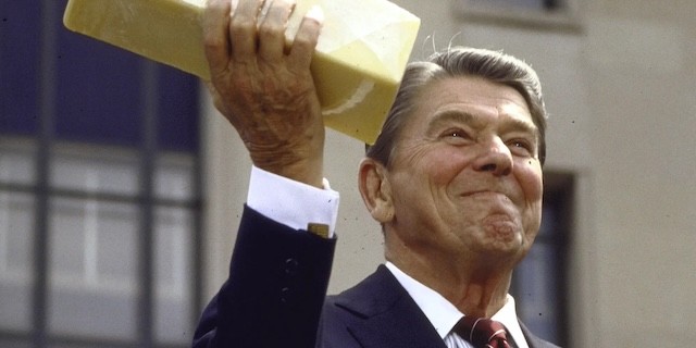 President Ronald Reagan holding a block of government cheese, a product that became a symbol of federal food programs aimed at supporting struggling families during his administration