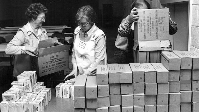 Volunteers distribute government cheese and other food products as part of a government assistance program in the 1980s, helping families across the country during tough economic times