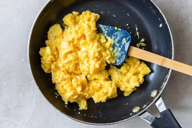 Perfectly cooked scrambled eggs in the pan. Whether with or without milk, the secret lies in gentle, low-heat cooking and constant stirring