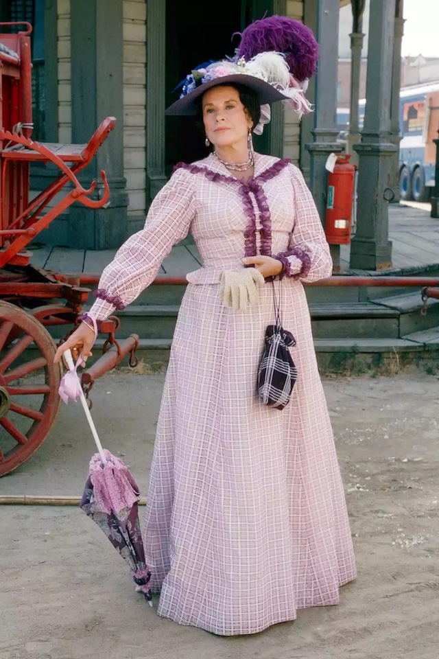 Katherine MacGregor as Harriet Oleson - The unforgettable Harriet Oleson, portrayed by Katherine MacGregor, in her elaborate period costume and her poised presence later in life.