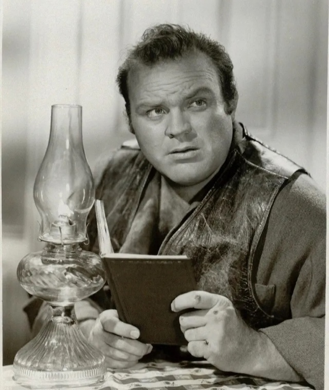 Dan Blocker as Hoss Cartwright: Here, Dan Blocker is seen in character as the kind-hearted Hoss Cartwright, reading in this thoughtful moment. Despite his imposing stature, Hoss was known for his gentle nature on Bonanza