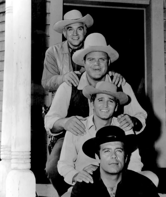 The Cartwrights posing on the steps of their ranch home in Bonanza, showcasing the unity and camaraderie of the show's central family