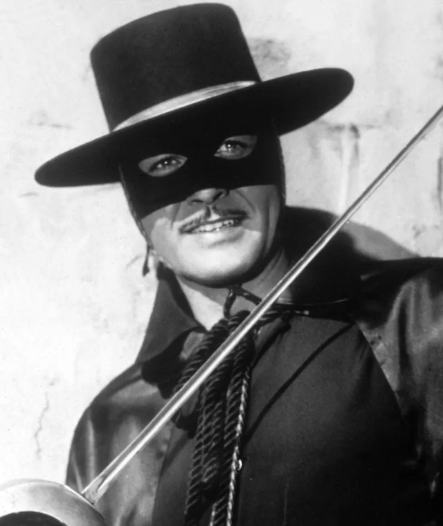 A classic shot of Guy Williams as Zorro, wearing his iconic mask and hat, wielding his signature sword