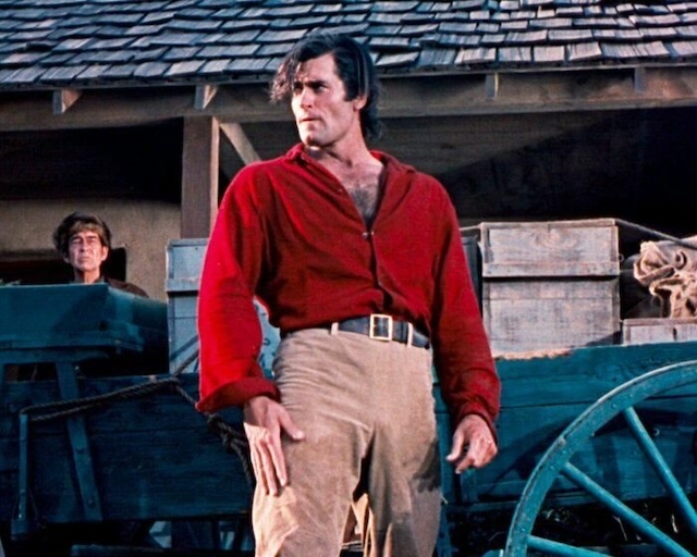 Clint Walker in his iconic red shirt, ready for action, as seen in one of his memorable film roles, displaying his commanding presence