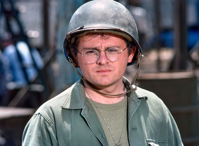 Radar O'Reilly, the beloved character from M*A*S*H, in a contemplative moment wearing his helmet, showcasing his signature earnest expression.