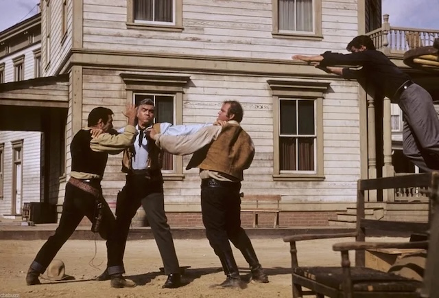 A Western-style brawl from Bonanza with actors engaged in a dramatic fight scene on the set of a frontier town