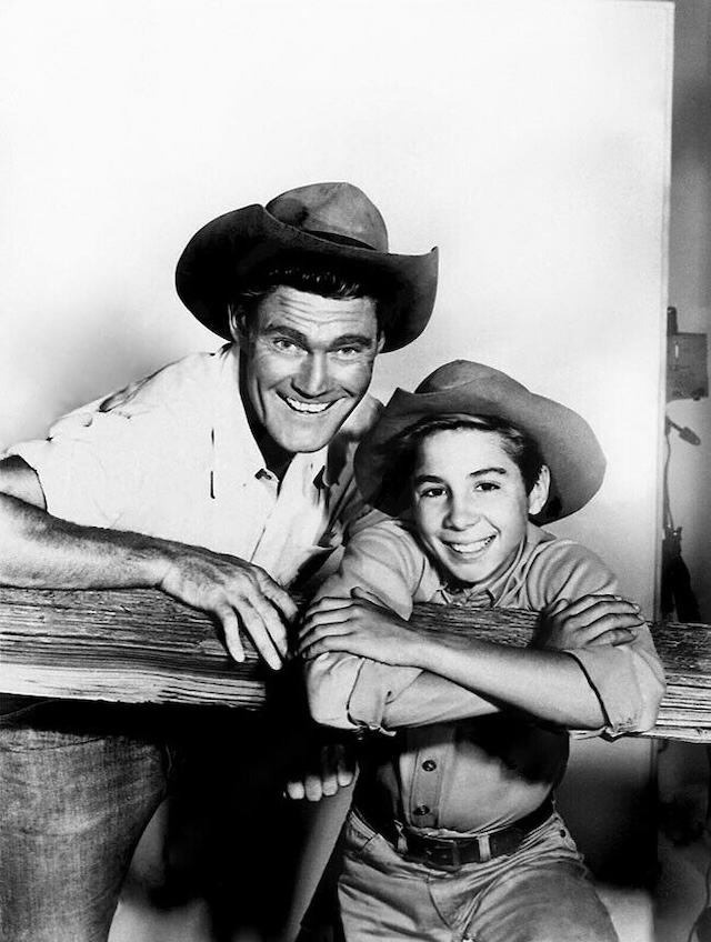 Chuck Connors and Johnny Crawford share a joyful moment behind the scenes of The Rifleman. Their close relationship off-camera mirrored the strong bond they portrayed on the show.