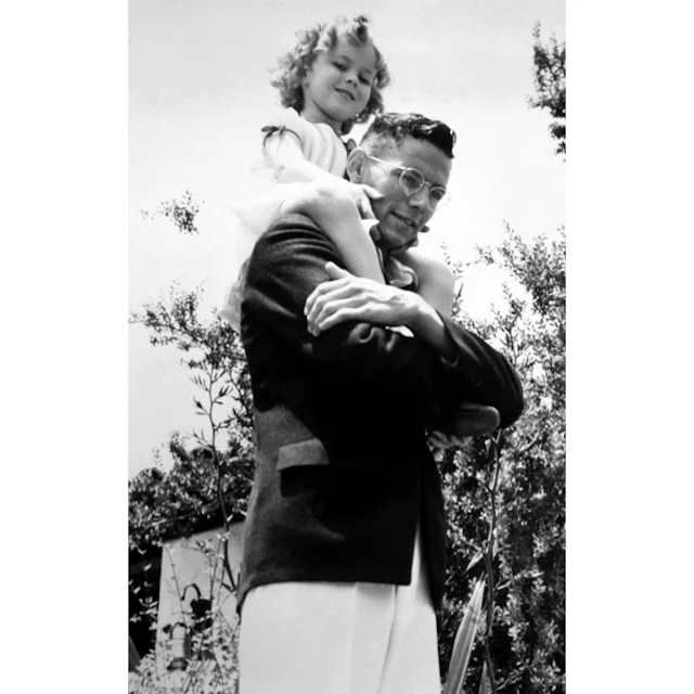 Shirley Temple riding on the shoulders of her older brother, John, showcasing the playful bond and sibling love they shared throughout her early years