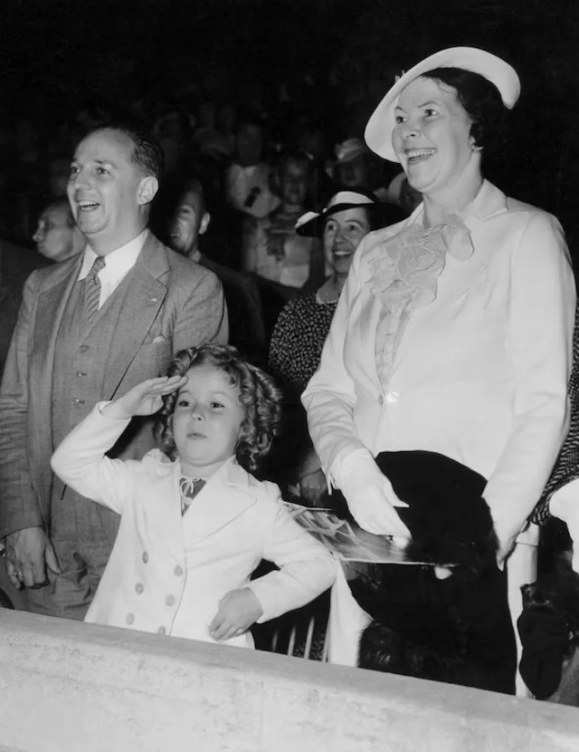 Shirley salutes with her parents, capturing the family's unity during her heyday