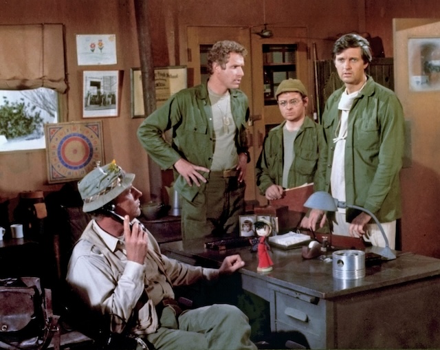 The team from M*A*S*H strategizes in the office. From left to right: Col. Potter, B.J. Hunnicutt, Radar O'Reilly, and Hawkeye Pierce.