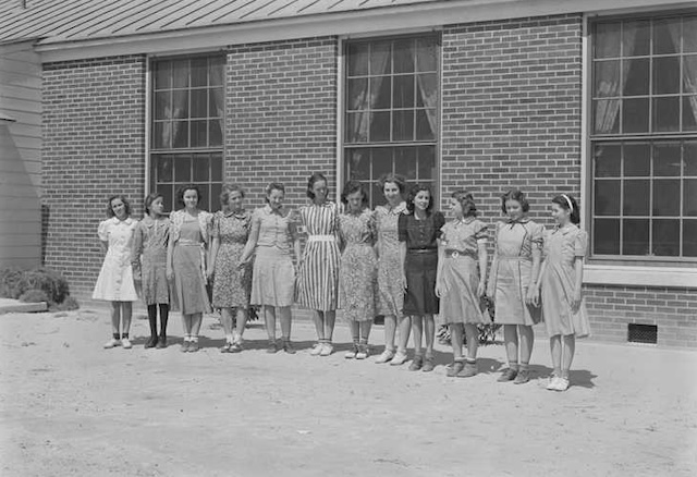 A line of students standing outside, each dressed in the garments they created in their Home Economics class, showcasing their hard work and creativity.