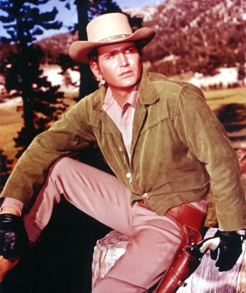 Michael Landon in his iconic role as "Little Joe," posing outdoors with his characteristic hat and confident demeanor