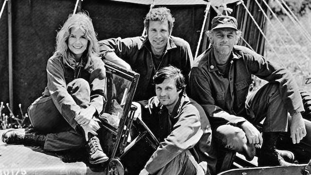 Trapper John, Hawkeye, Major Margaret “Hot Lips” Houlihan, and Colonel Blake—four of the original ensemble cast members—pose for a memorable photo during the early seasons of M*A*S*H.