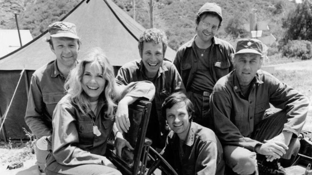 The cast of M*A*S*H together, capturing a rare light-hearted moment amidst the intensity of the show. This ensemble cast was critical to the success and evolution of the series