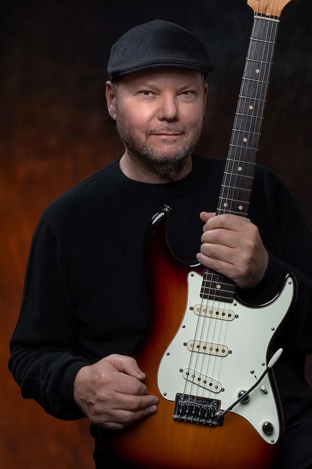 A recent photograph of Christopher Cross holding his guitar, representing his enduring passion for music despite the challenges he faced in his career and life