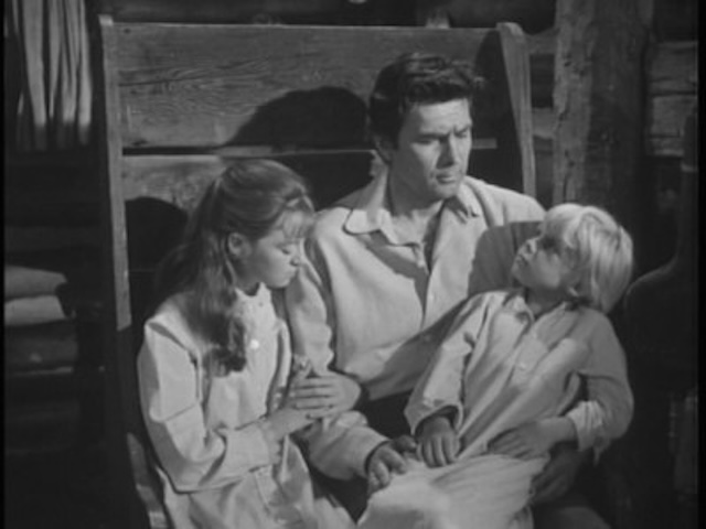 Daniel Boone (Fess Parker) in an intimate moment with his on-screen children, highlighting the family-centered themes of the show.