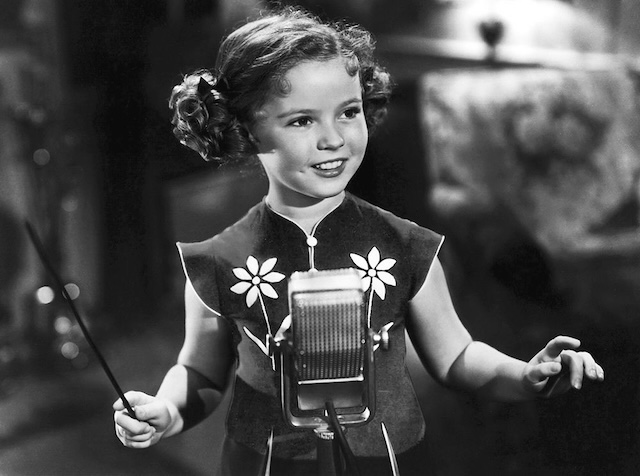 In this iconic shot, Shirley Temple is seen directing with her baton, a nod to her multi-talented performances