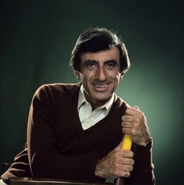 Jamie Farr, dressed casually in a sweater, showcasing the actor's warm personality outside of his legendary M*A*S*H role as the comedic, cross-dressing corporal