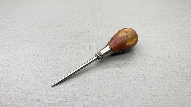 A well-preserved vintage awl with a sleek metal tip and polished wooden grip