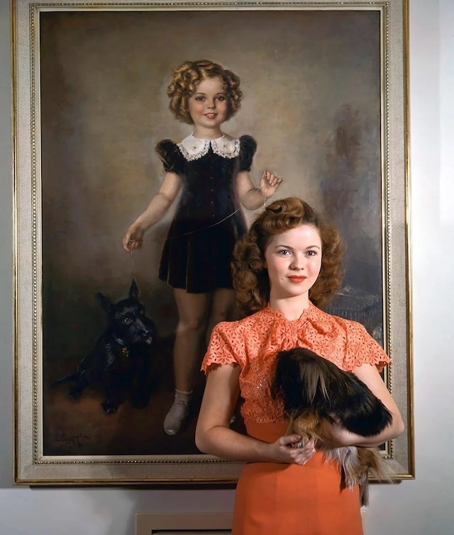 A grown-up Shirley Temple stands next to a portrait of herself as a child star, reflecting her transition from an actress to a diplomat and public figure