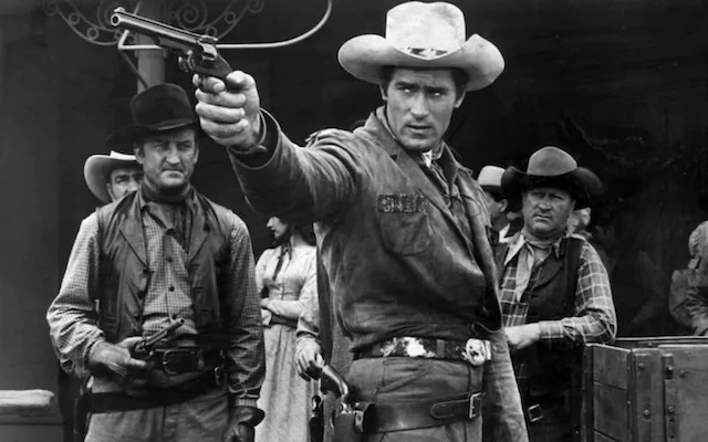 In a tense scene from Cheyenne, Clint Walker draws his gun, ready to take on anyone who disturbs the peace, as the sheriff of a small town.