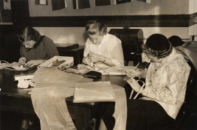 A group of women concentrating on their sewing assignments in a Home Economics class, learning skills that would serve them for years to come.