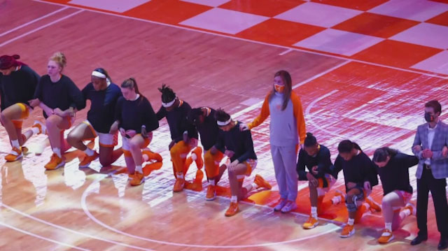 A team of basketball players kneeling in solidarity during the National Anthem, joining the movement that protests racial inequality and systemic oppression.