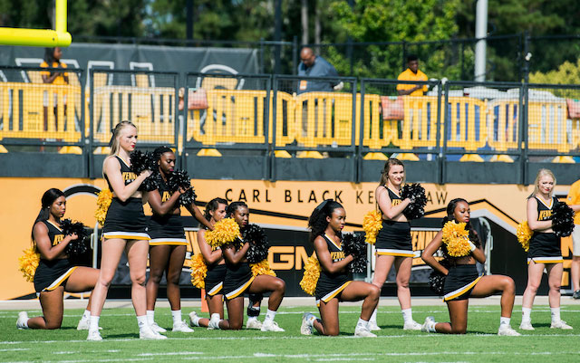 Cheerleaders take a knee on the football field, using their platform to raise awareness about police brutality and social injustice.