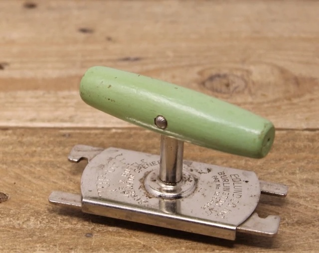 A charming vintage jar opener with a green handle, showcasing the variety of designs available during its time.