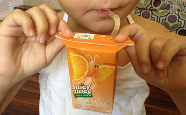 A child using the carton’s flaps to hold the juice box securely while drinking, preventing any messy spills.