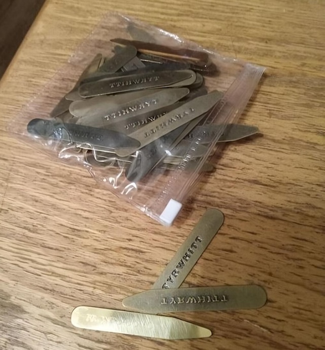 A pile of vintage collar stays, carefully stored in a small plastic bag. Each stay is stamped with "TURNWIT."