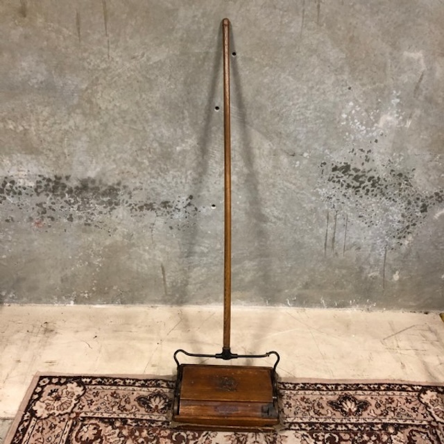 A closer look at the intricate design of this antique carpet sweeper, showcasing the craftsmanship that was common in household tools from a bygone era.