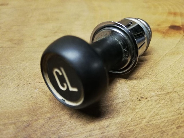 Another view of a vintage car cigarette lighter, this one labeled "CL" for cigarette lighter, with its typical black button and metal casing