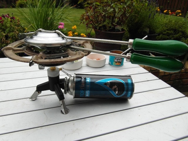 A Nutbrown sandwich toaster in action over a portable stove, demonstrating its versatility and convenience for outdoor cooking.