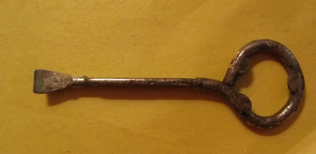 An aged paint can opener with a distinctly rounded handle, showing signs of frequent use over the years