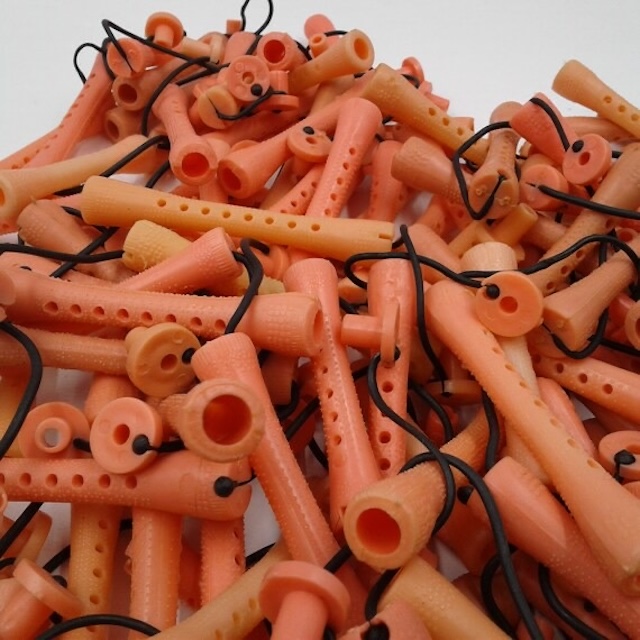 A pile of vintage orange perm rods, complete with the elastic bands used to secure them in place.