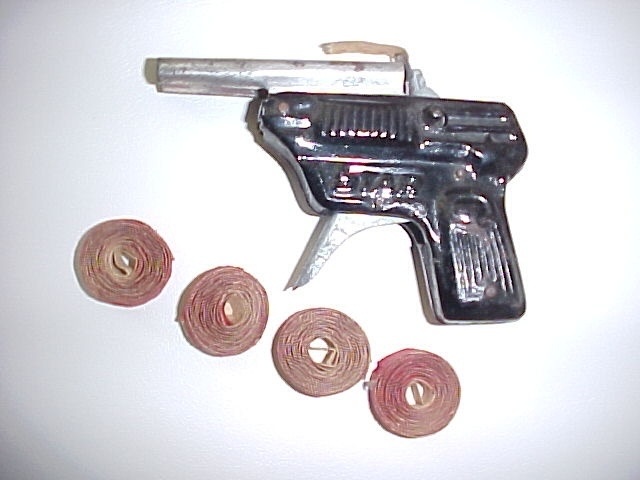 A classic cap gun with a collection of cap rolls, just like the ones that brought excitement to playtime years ago