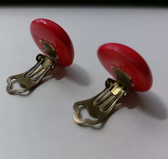 These red clip-on earrings with a bold circular design bring back memories of classic elegance from the mid-20th century.