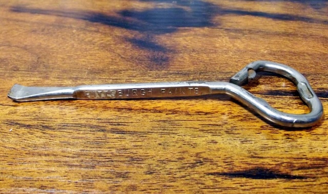 An engraved paint can opener, showcasing craftsmanship from a bygone era, likely part of a paint brand's promotional tools