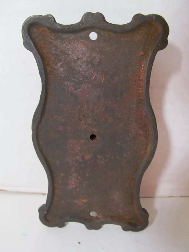 The aged and rusted back of the Mueller dial, revealing its sturdy cast iron construction from the early 1900s.