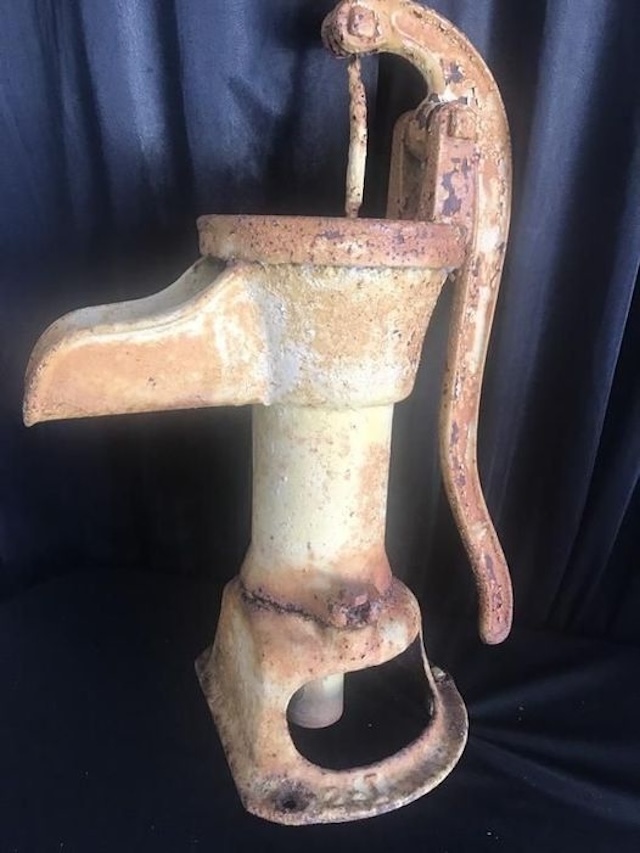 An antique cast iron Fairbury hand pitcher pump with a charming patina, showcasing the rustic durability of past eras.