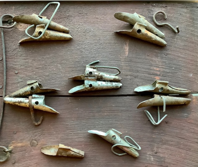 A close-up shot of several vintage metal spiles, showing their curved and hook-like designs, once attached to maple trees to collect sap.