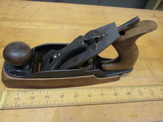 This antique wood plane, complete with a wooden handle and solid metal body, harks back to an era when craftsmanship and hand tools were inseparable