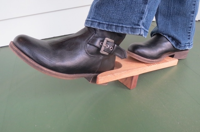 Demonstrating how the wooden boot jack is used, providing leverage to easily pull off snug boots