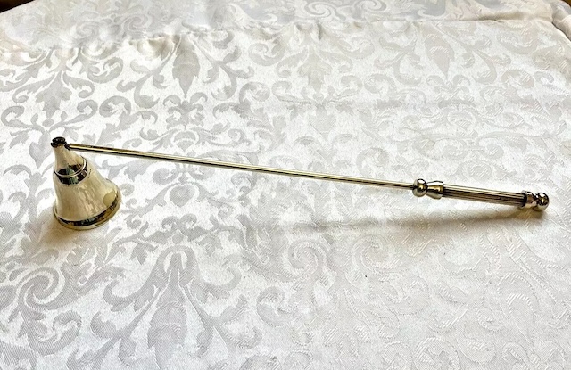 A silver-toned candle snuffer, with its simple yet refined design, once a staple in homes before the advent of electric lights.