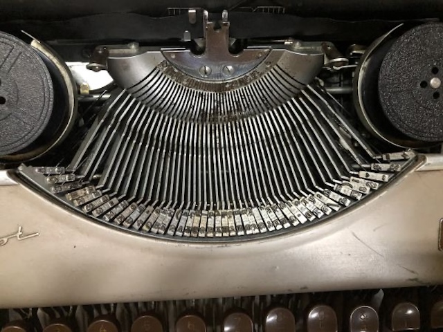 A close-up view of the intricately aligned typebars of an old typewriter