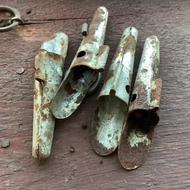 Four weathered vintage spiles grouped together on a wooden surface, illustrating their sturdy yet rusted construction, symbolizing a bygone era of syrup-making.