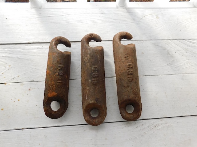 Three well-worn antique window sash weights, showing their age and enduring utility in traditional window mechanisms.