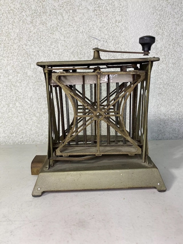 This compact and sturdy vintage toaster features an intricate grid design, a hallmark of early electric toasting devices.