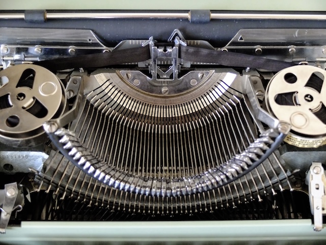 Rows of typebars on an old typewriter, waiting for the next letter to strike.